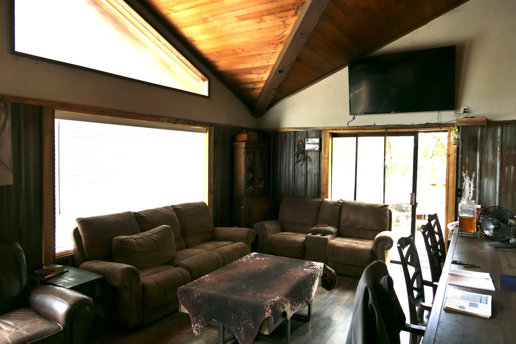 The lodge great room — couches around a cowhide table under the vaulted wood ceiling, with sliding doors to the deck