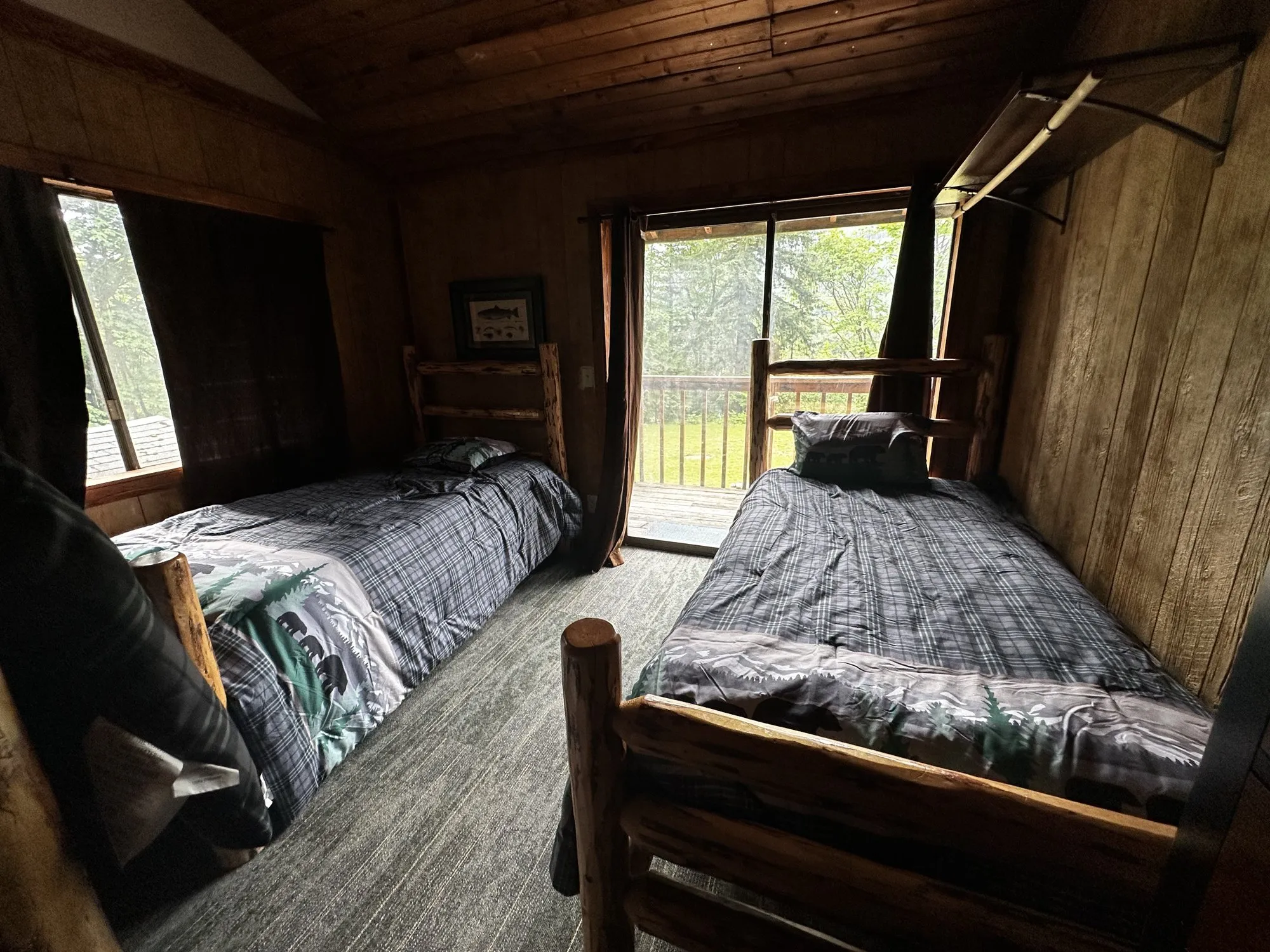 Another shared bedroom with two log-frame beds and a sliding door opening to the pasture
