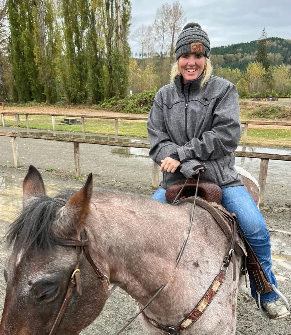 KC Letterman on horseback at the ranch, mountains behind