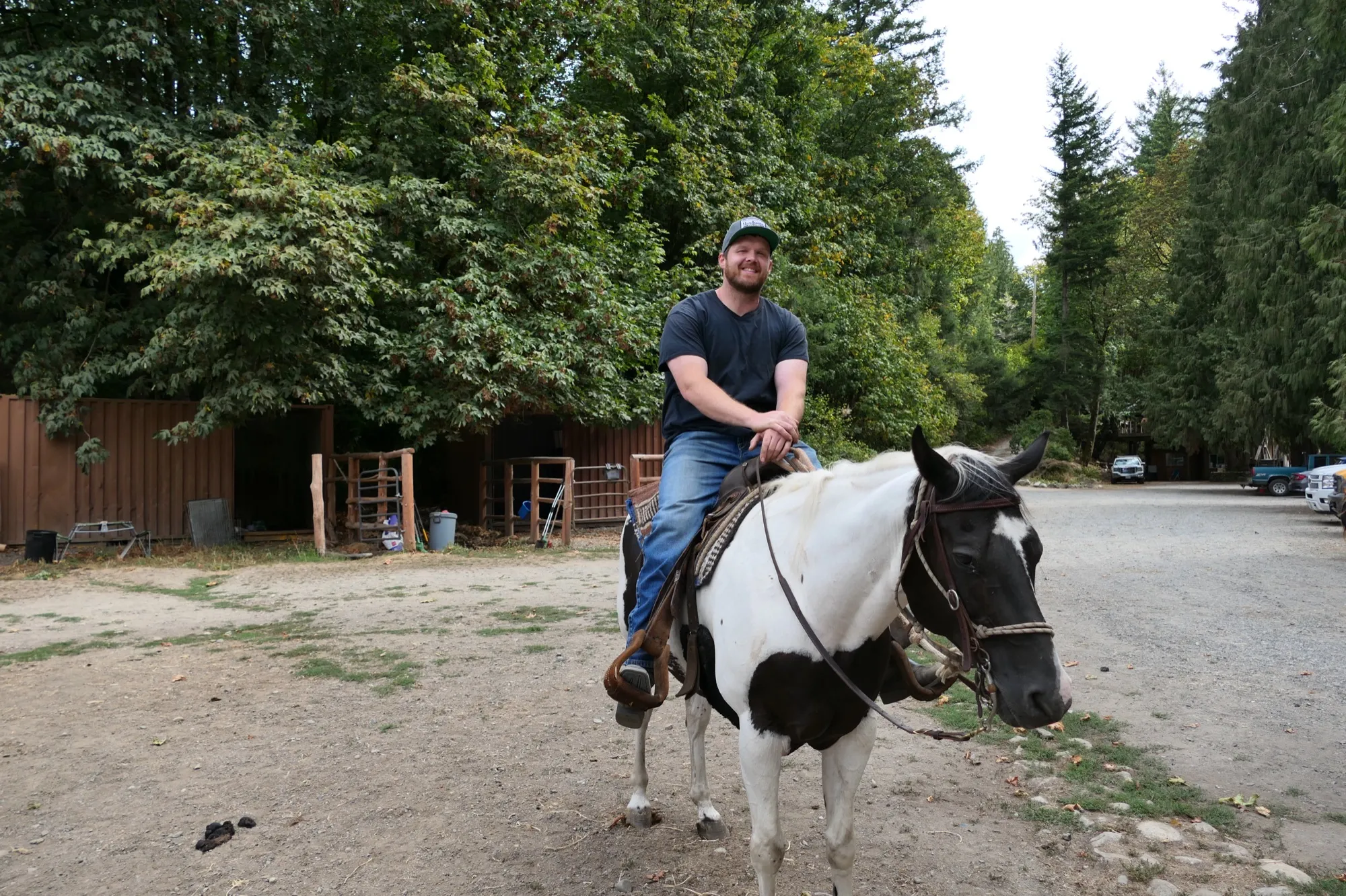 A smiling resident on a paint horse in front of the barn