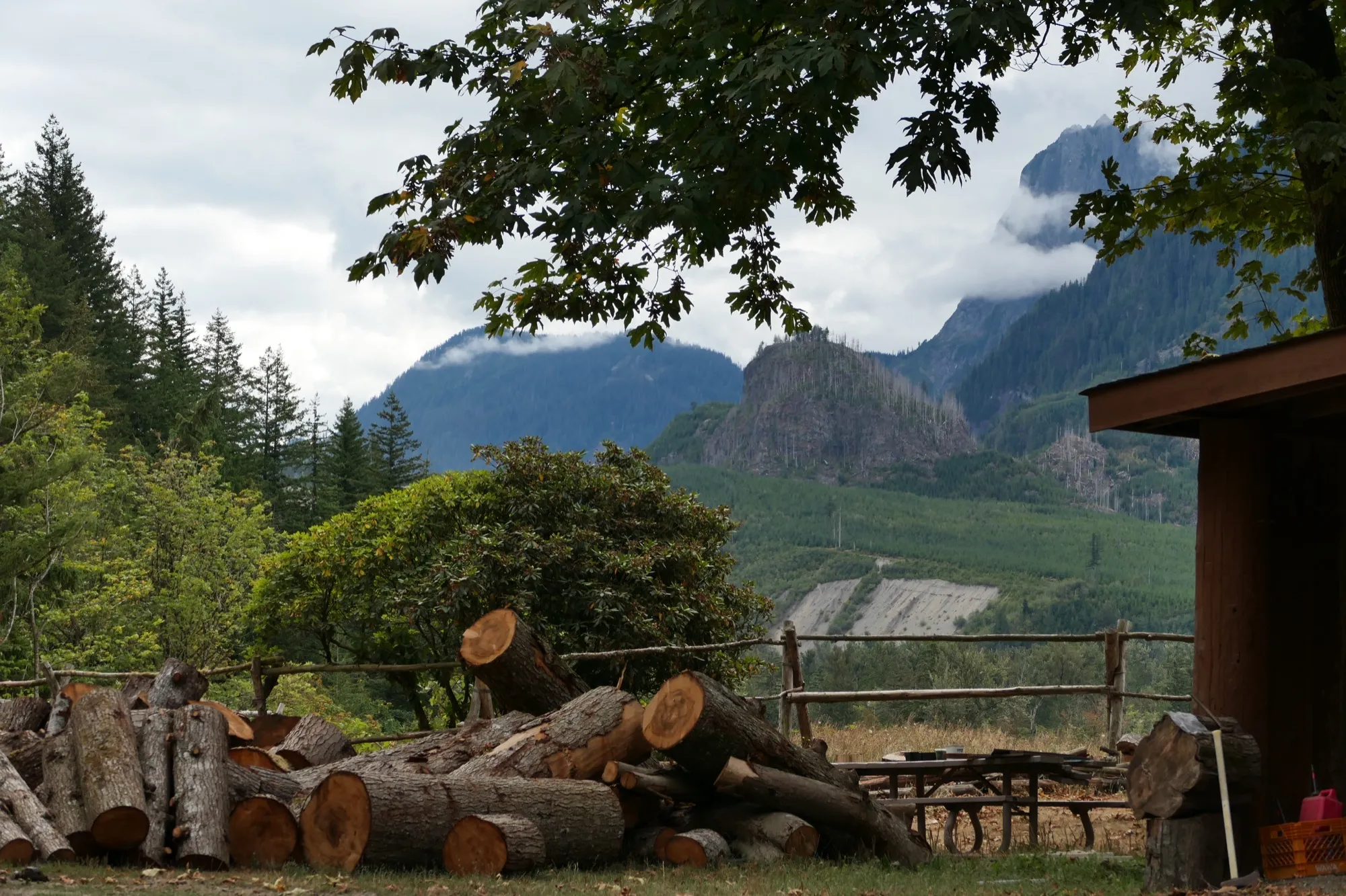 A woodpile by the lodge with the mountains rising behind